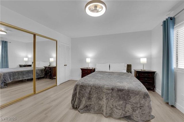 bedroom with baseboards, light wood finished floors, and a closet