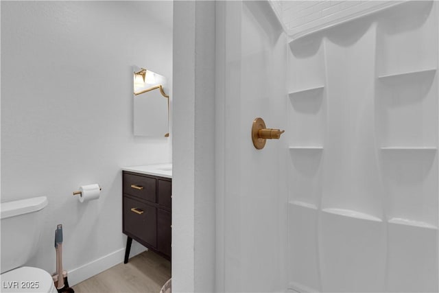 bathroom featuring vanity, wood finished floors, a shower, toilet, and baseboards