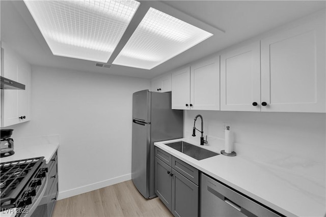 kitchen featuring light countertops, appliances with stainless steel finishes, a sink, and light wood finished floors