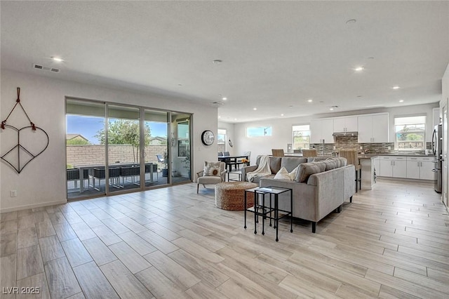living area with a healthy amount of sunlight, light wood-type flooring, and recessed lighting