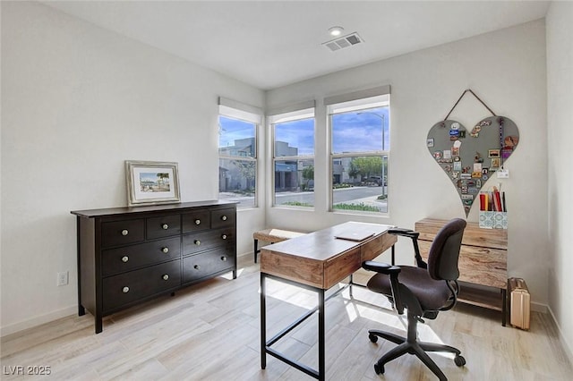 office space featuring baseboards, light wood-type flooring, and visible vents