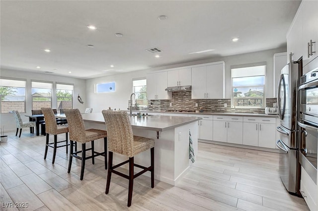 kitchen featuring stainless steel appliances, a breakfast bar, a healthy amount of sunlight, and a sink