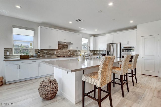 kitchen with visible vents, decorative backsplash, appliances with stainless steel finishes, and under cabinet range hood
