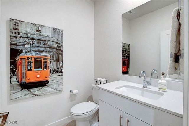 bathroom featuring vanity, baseboards, visible vents, and toilet