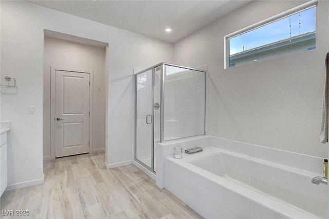 full bath featuring a shower stall, wood finished floors, a garden tub, and vanity