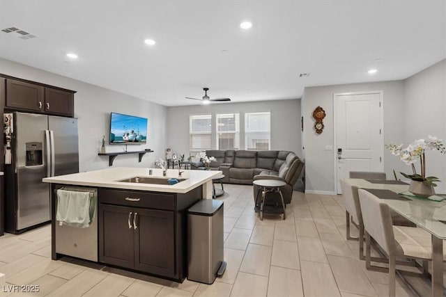 143 Aqua Commons Ln, Henderson, NV 89015 - kitchen featuring appliances with stainless steel finishes, dark brown cabinets, a sink, light countertops, and an island with sink