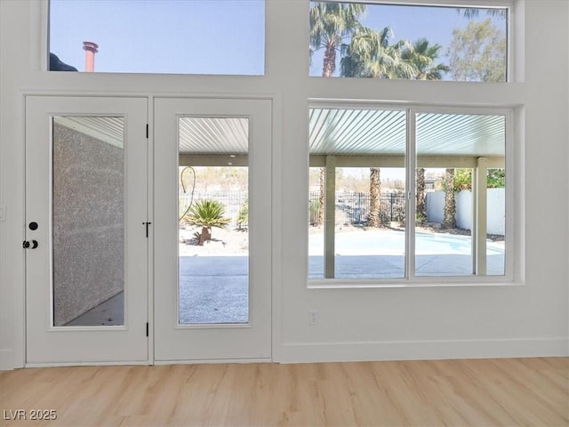 doorway to outside featuring baseboards, a wealth of natural light, and wood finished floors