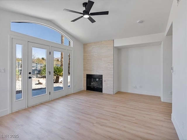 unfurnished living room featuring baseboards, ceiling fan, light wood-type flooring, and lofted ceiling