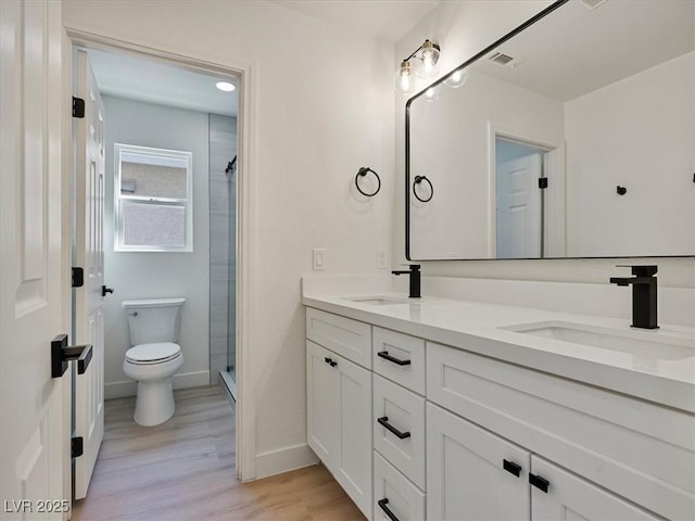 bathroom featuring a sink, toilet, wood finished floors, and visible vents