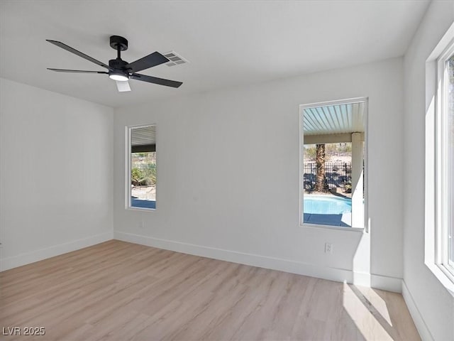 empty room with a healthy amount of sunlight, wood finished floors, and visible vents