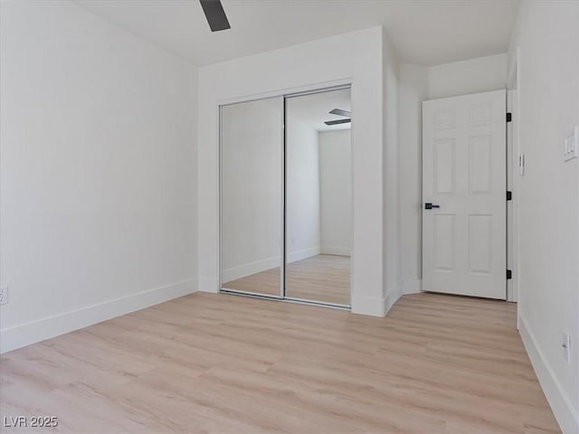 unfurnished bedroom featuring a closet, a ceiling fan, light wood-style flooring, and baseboards