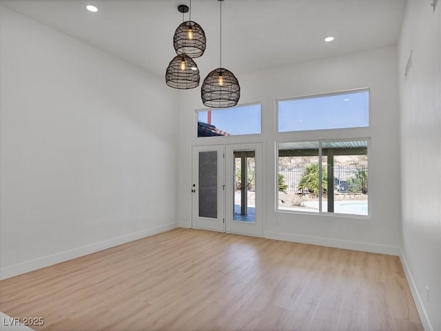 interior space with recessed lighting, baseboards, wood finished floors, and a towering ceiling