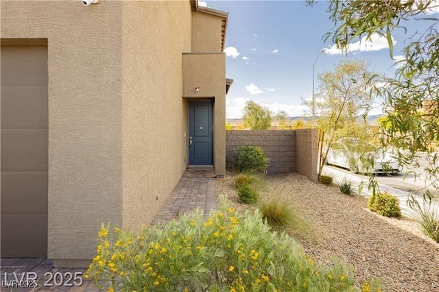 property entrance featuring fence and stucco siding