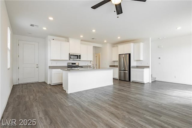 kitchen with visible vents, wood finished floors, baseboards, open floor plan, and appliances with stainless steel finishes