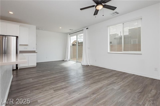 unfurnished living room featuring a ceiling fan, dark wood-type flooring, and visible vents