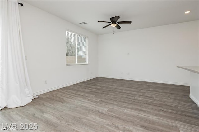 unfurnished room with a ceiling fan, baseboards, visible vents, and wood finished floors