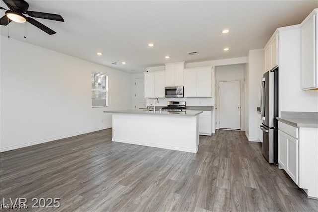 kitchen with a sink, stainless steel appliances, recessed lighting, and wood finished floors