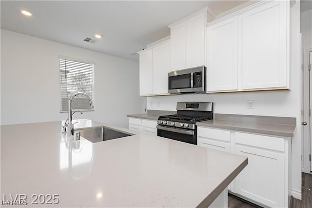 kitchen with visible vents, a sink, appliances with stainless steel finishes, and white cabinets