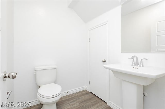 half bathroom featuring baseboards, wood finished floors, and toilet