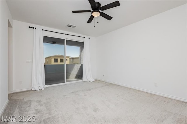 carpeted empty room with baseboards, a ceiling fan, and visible vents