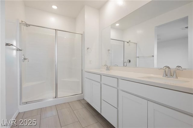 full bathroom with double vanity, a sink, recessed lighting, and a shower stall