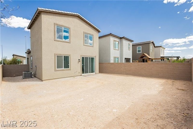 back of property with a fenced backyard, stucco siding, and central AC