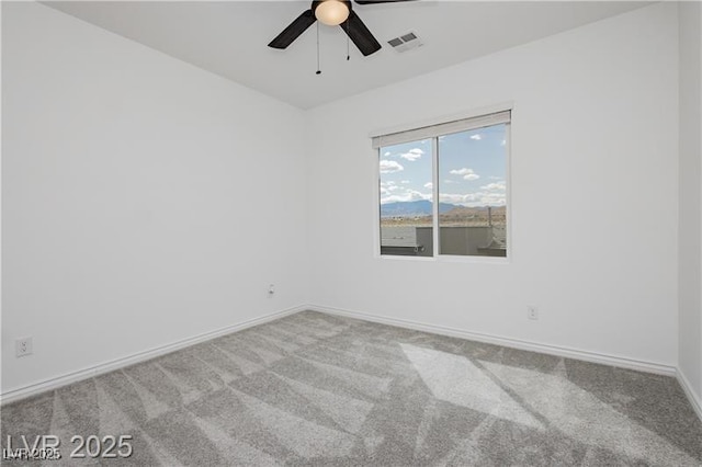 carpeted empty room with baseboards, a ceiling fan, and visible vents
