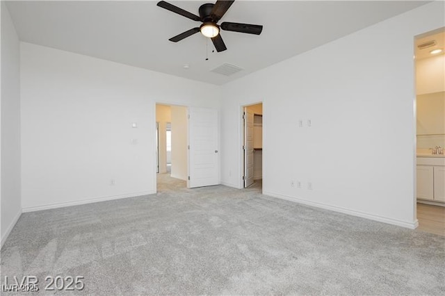 unfurnished bedroom with baseboards, ensuite bathroom, light carpet, and a spacious closet