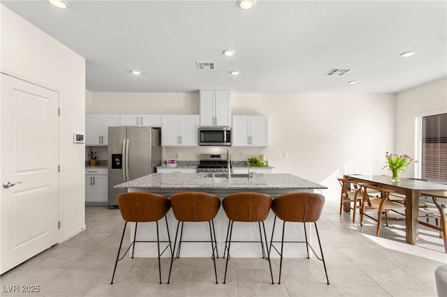 kitchen featuring a sink, appliances with stainless steel finishes, a kitchen bar, and visible vents