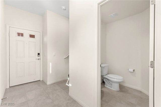 bathroom with baseboards, tile patterned flooring, and toilet