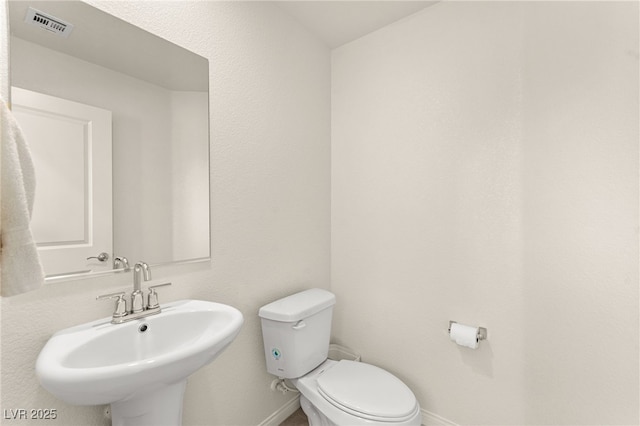 bathroom featuring toilet, baseboards, visible vents, and a sink