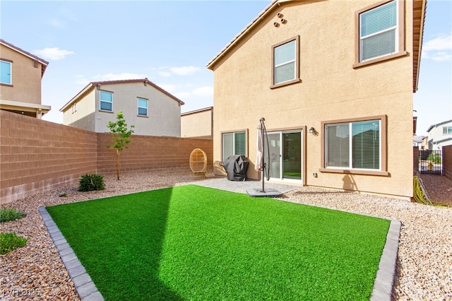 back of property with a fenced backyard, stucco siding, a yard, and a patio area