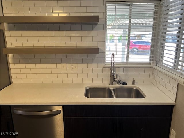 kitchen featuring stainless steel dishwasher, decorative backsplash, a sink, and light countertops