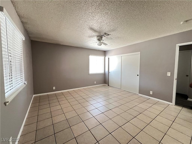 unfurnished bedroom with ceiling fan, a textured ceiling, visible vents, light tile patterned floors, and a closet