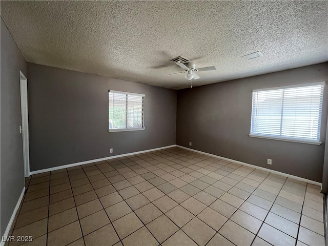 spare room featuring a textured ceiling, ceiling fan, visible vents, and baseboards