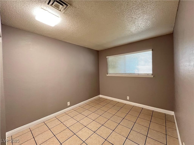 spare room featuring visible vents, baseboards, a textured ceiling, and light tile patterned floors