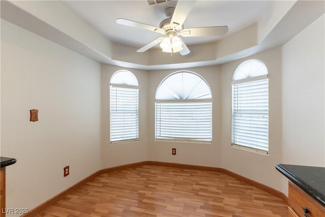 3510 Judah Way, Las Vegas, NV 89147 - unfurnished dining area featuring a ceiling fan, baseboards, a raised ceiling, and light wood-style floors