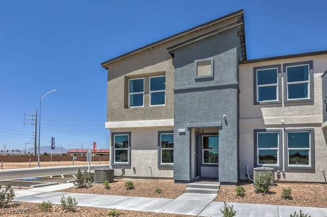 contemporary home featuring cooling unit and stucco siding