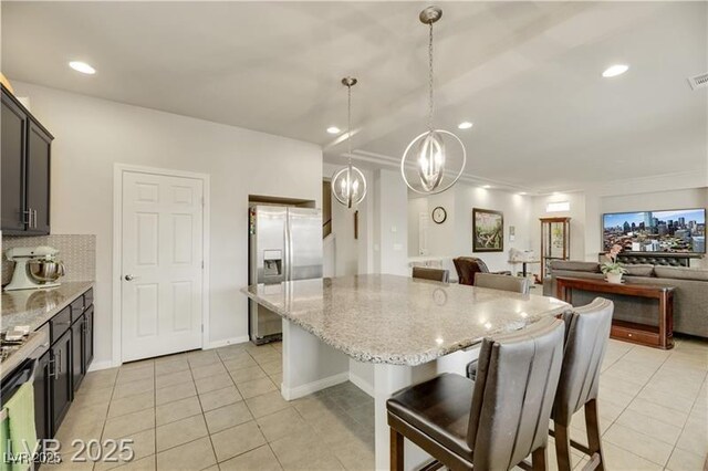 kitchen with a kitchen island, a breakfast bar, light tile patterned floors, and stainless steel fridge with ice dispenser