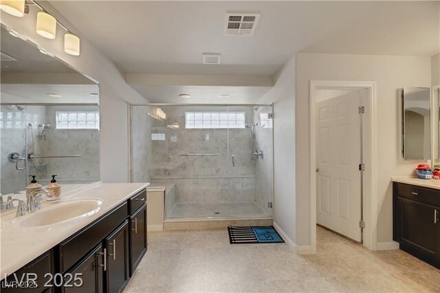 bathroom featuring a sink, baseboards, two vanities, a shower stall, and visible vents