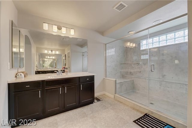 full bathroom featuring vanity, baseboards, a shower stall, and visible vents