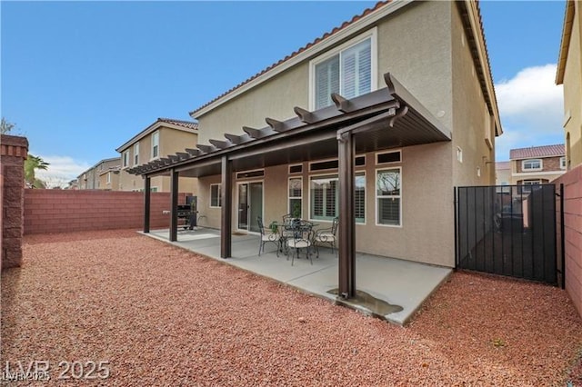 back of house featuring a gate, a fenced backyard, a patio area, and stucco siding
