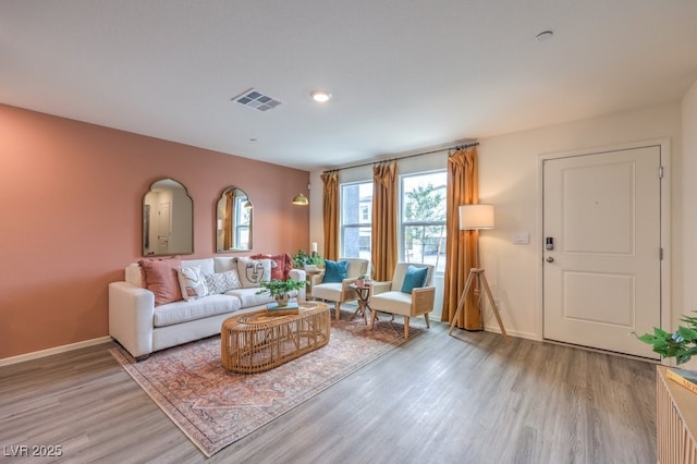living room featuring visible vents, light wood-style floors, and baseboards