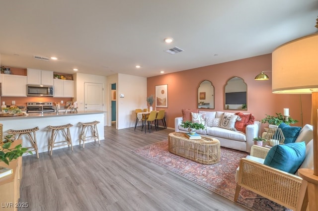 living room with visible vents, recessed lighting, and light wood finished floors