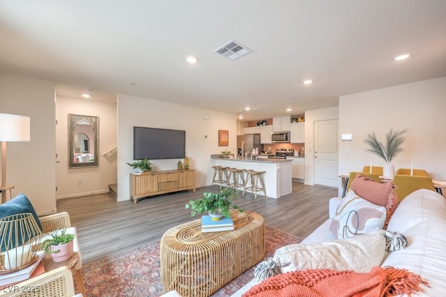 living area with visible vents, recessed lighting, light wood-style floors, and baseboards