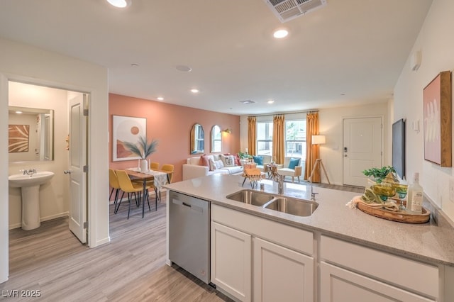 kitchen featuring visible vents, open floor plan, white cabinets, a sink, and dishwasher