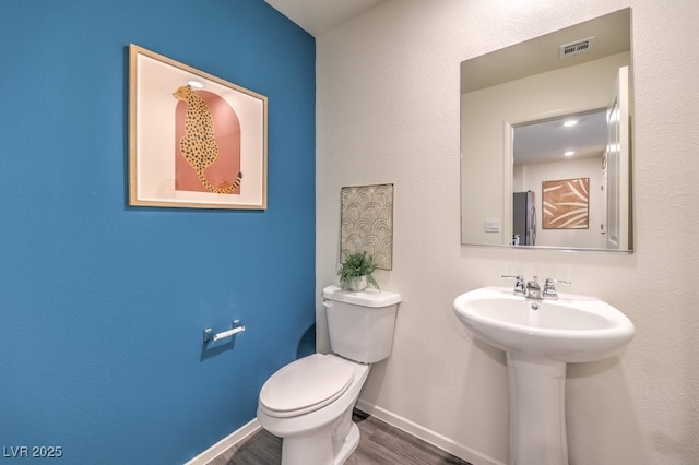 bathroom with visible vents, wood finished floors, a sink, baseboards, and toilet