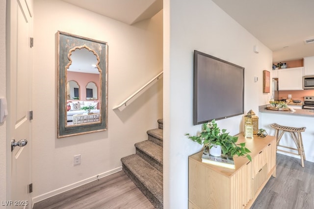 staircase with visible vents, baseboards, and wood finished floors