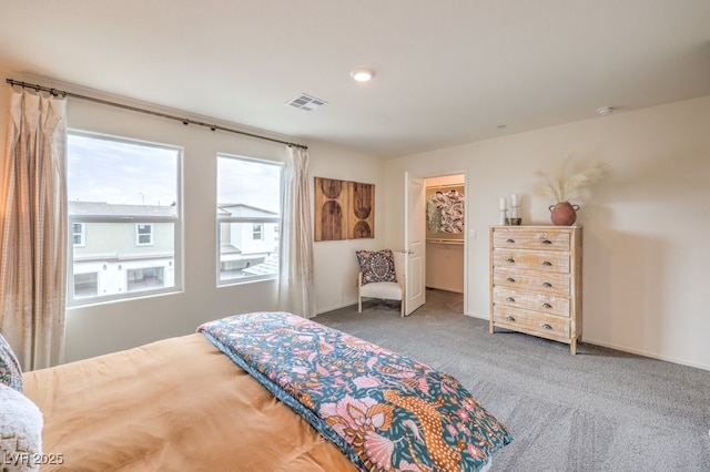 carpeted bedroom featuring a walk in closet, baseboards, and visible vents