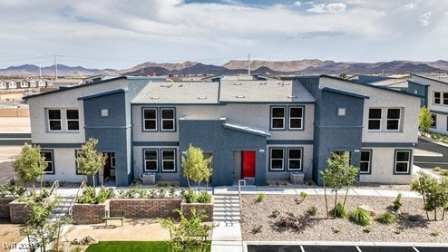 rear view of house featuring uncovered parking, a mountain view, and stucco siding